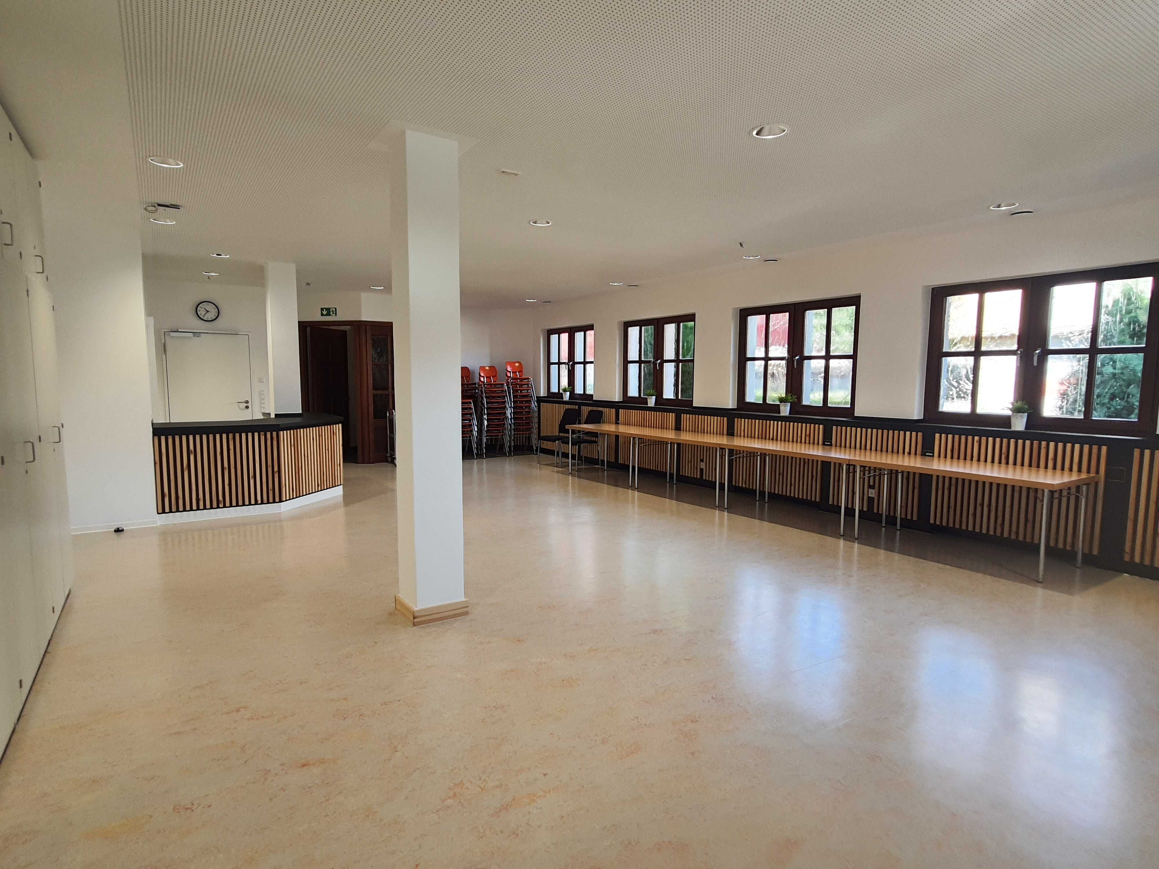 Seminarraum mit Tischen vor einer Fensterreihe und kleiner Theke